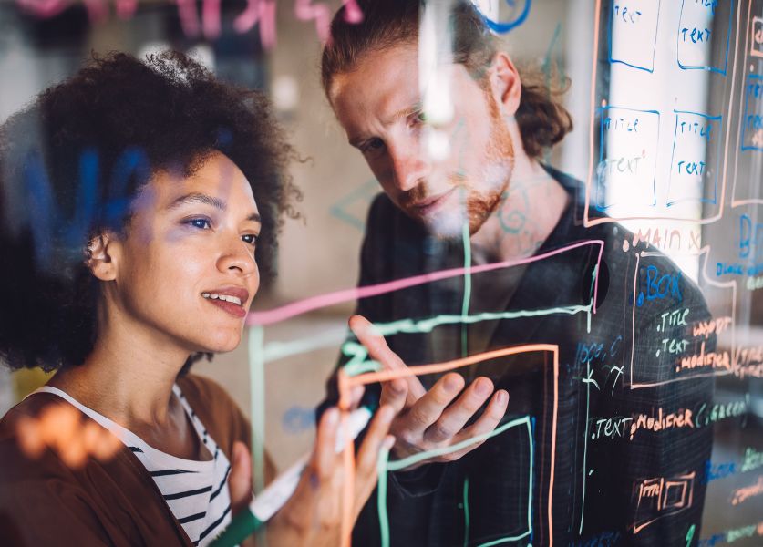 ragazza e ragazzo scrivono su una lavagna in ufficio